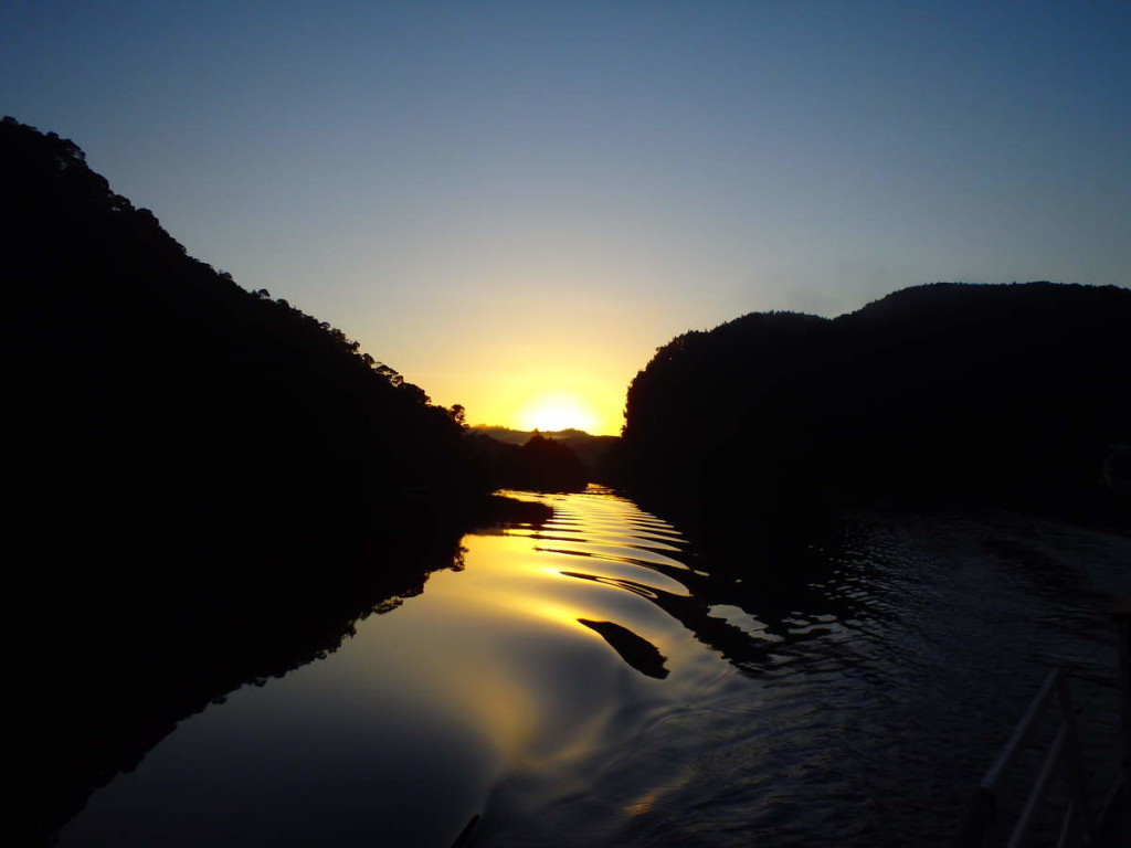 The sun emerges above Butler Island on the Gordon River - at Water by Nature Tasmania, Franklin River Rafting™
