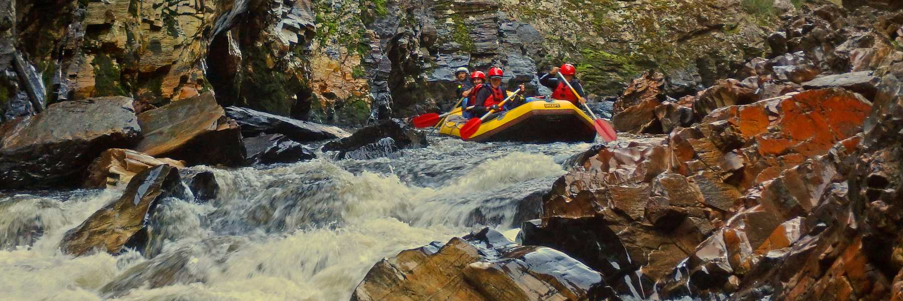 Raft in the Descension Gorge with red quartzite rocks, Franklin River Tasmania